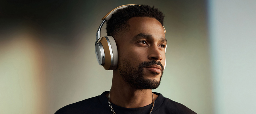 A man wearing silver and tan colored Bowers & Wilkins headphones