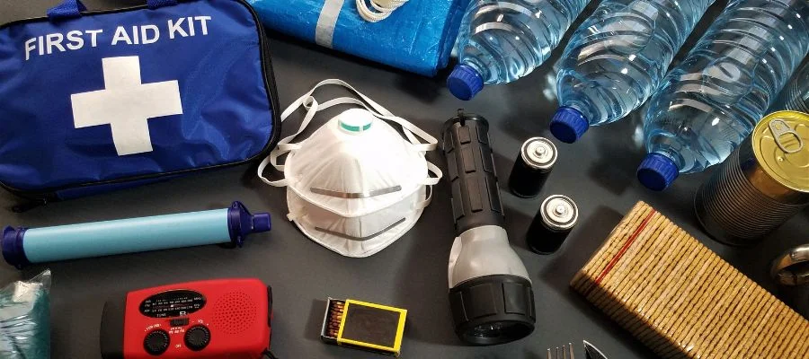Image of a first aid kit, water bottles, a flashlight, radio and more