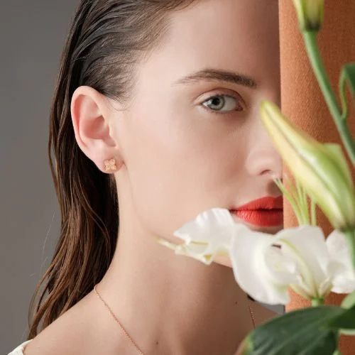 Tight shot on a half of a womans face behind a floral arrangement with a Roberto Coin Earring in