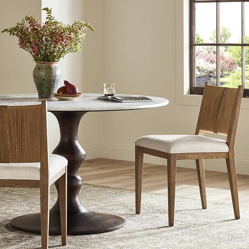 A beautifully arranged dining table with chairs and a vibrant vase of flowers