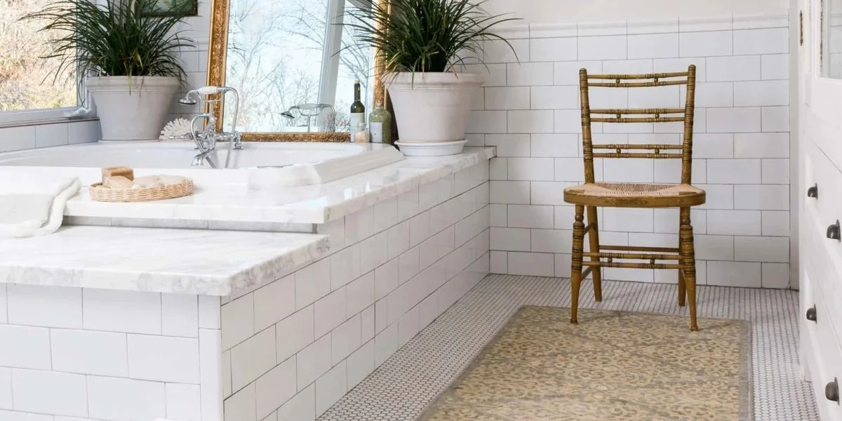 A bathroom tiled with white subway tile featuring a large soaking tub. A long runner sits alongside the bath tub.