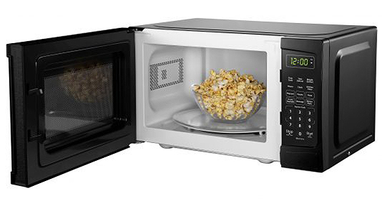 Left angle view of open microwave with bowl of popcorn inside.