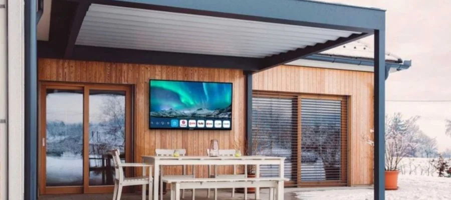 An outdoor TV hung on the wall of a home with snow on the ground outside