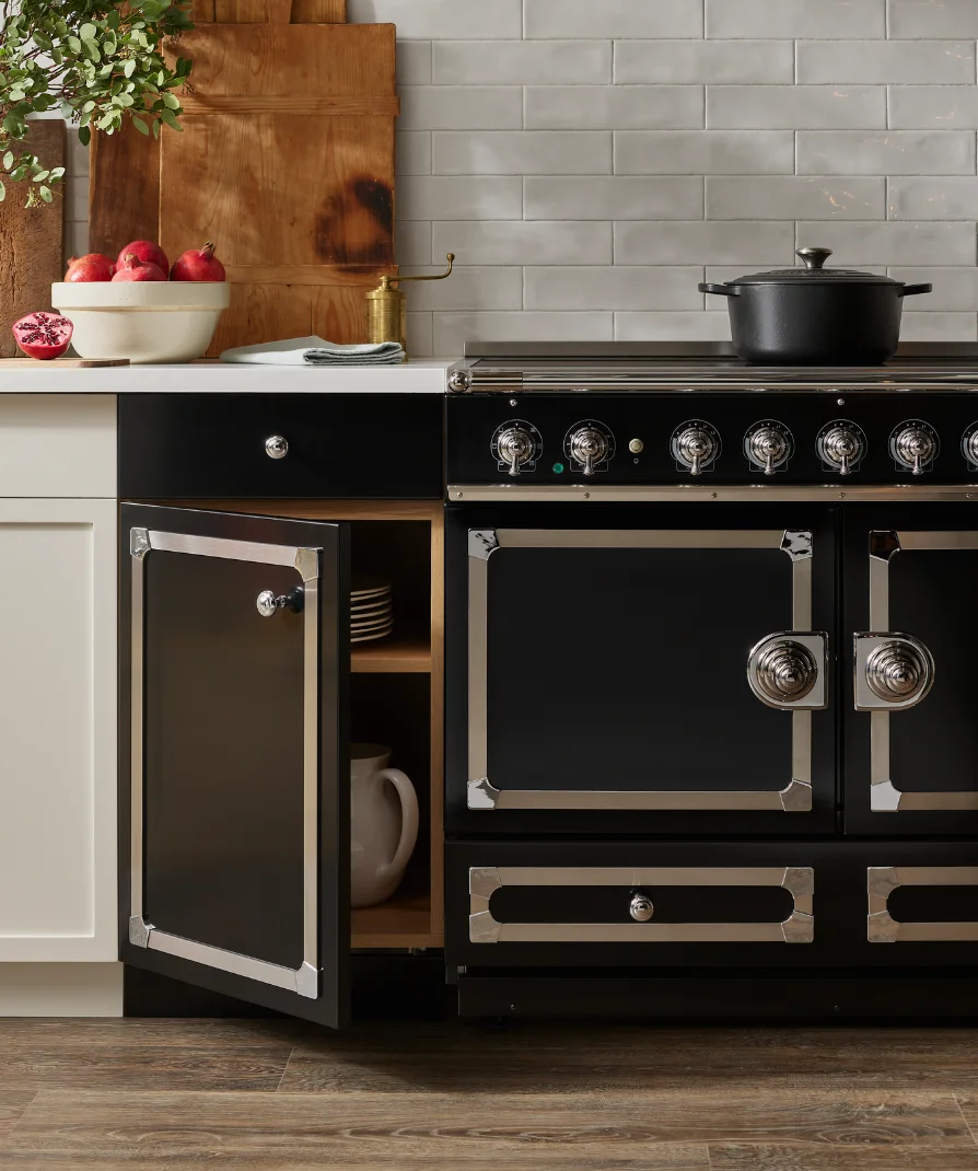 Black La Cornue range with open cabinet door showing dish storage