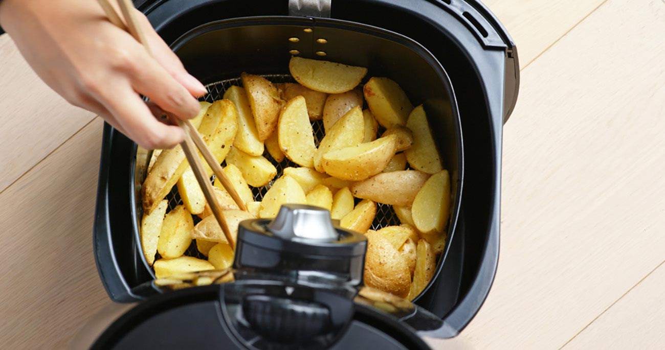 Person Placing Potatoes in Air Fryer