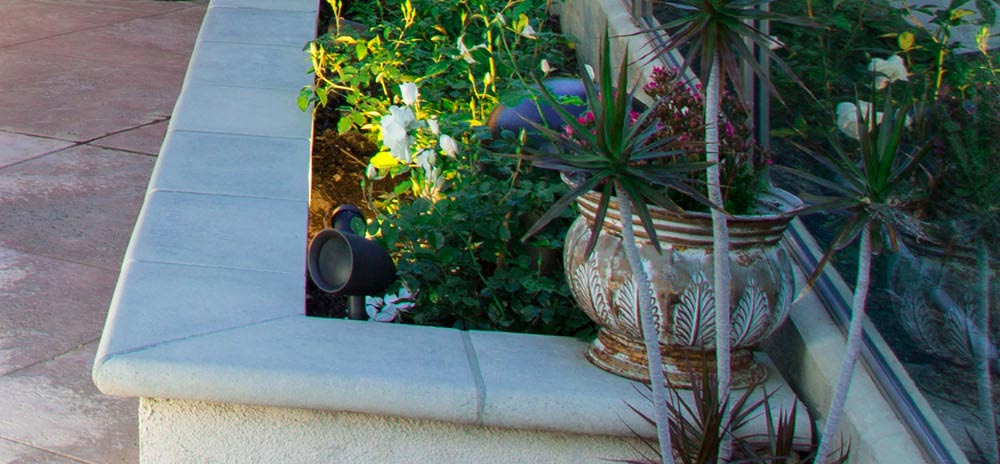 Black outdoor speaker installed amongst landscaping