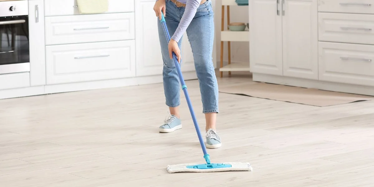person wearing jeans dry mopping kitchen floor