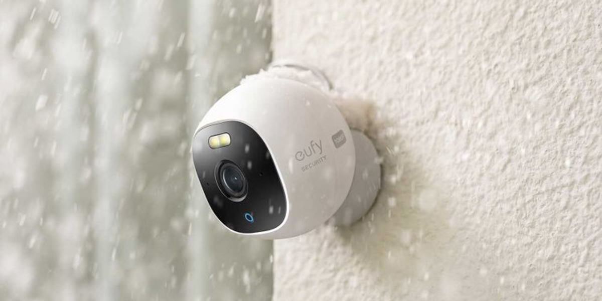 A white Eufy security camera installed outside of a home while it's actively snowing outside.