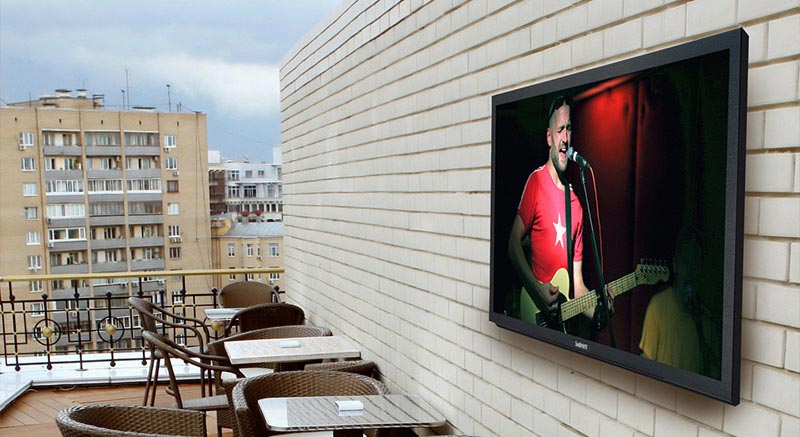 Outdoor TV in full sun against brick wall