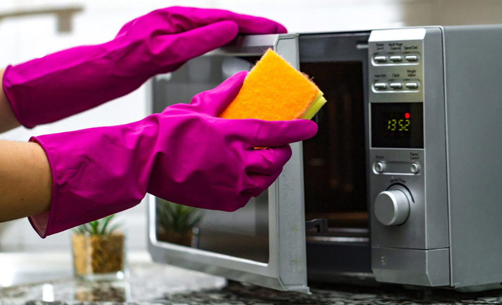 cleaning microwave wearing gloves