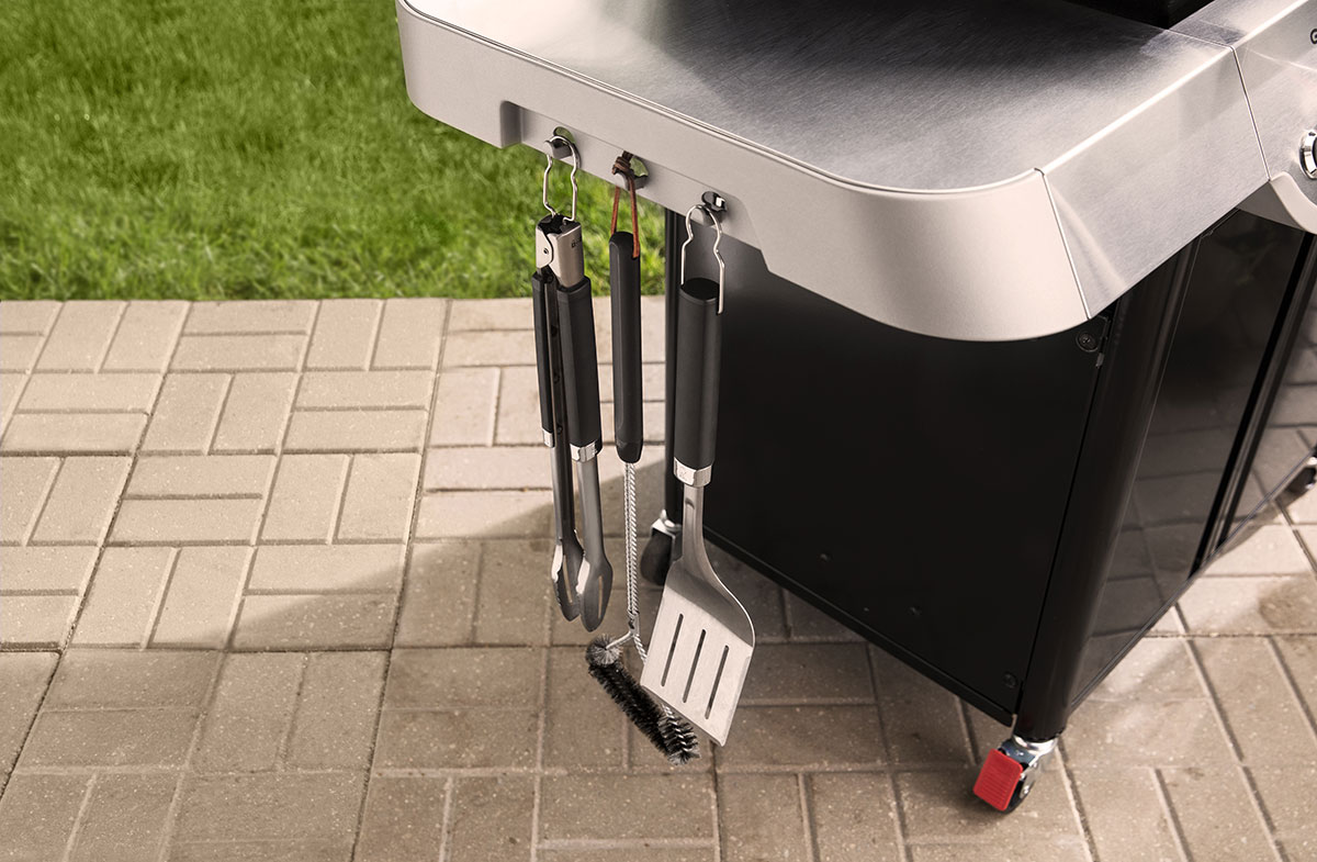 Tools hung on the side of the grill.