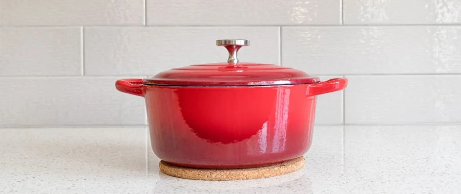 Covered red Dutch oven sitting on kitchen counter