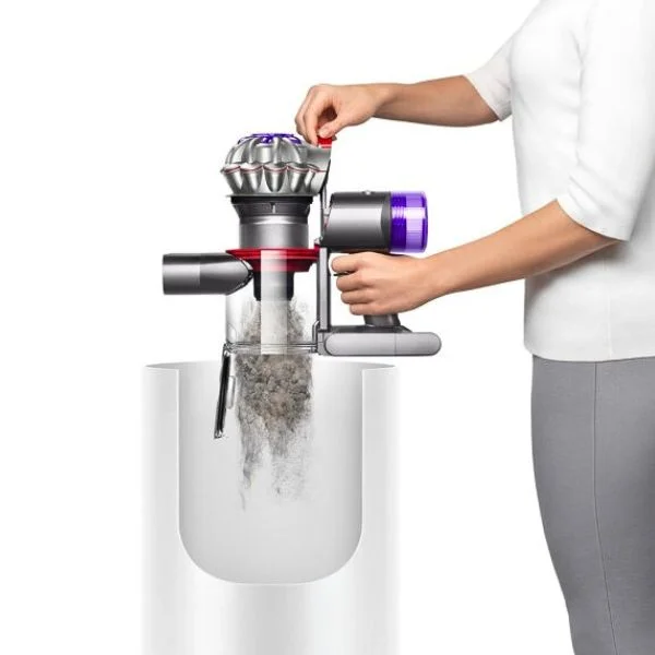Side view of a person in a white shirt emptying the Dyson V8 over a trash bin.