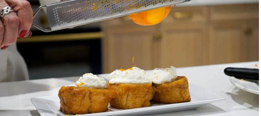 A plate of orange french toast with orange grated above the toast
