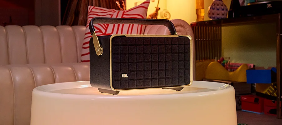 The JBL Authentics 300 speaker sitting on a glowing white table in front of a leather couch