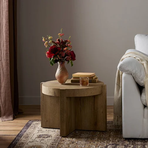A white couch beside a wooden end table adorned with flowers