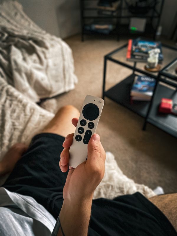 Close up on a person holding an apple TV remote showcasing him turning on the apple tv to watch
