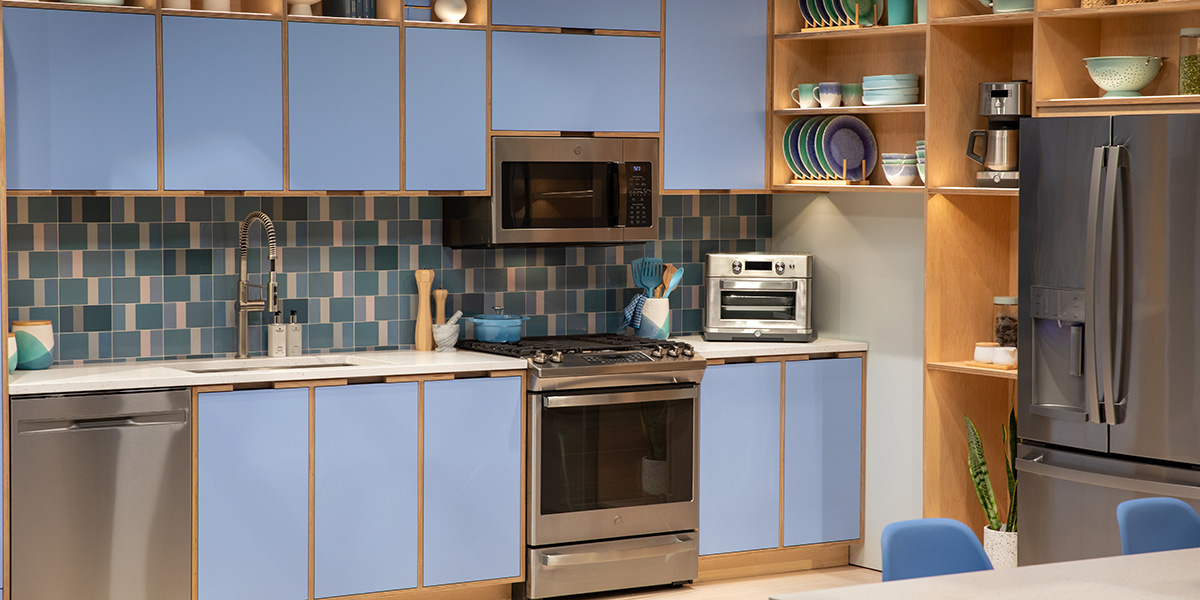 A blue kitchen with GE appliances and an expressive tiled backsplash
