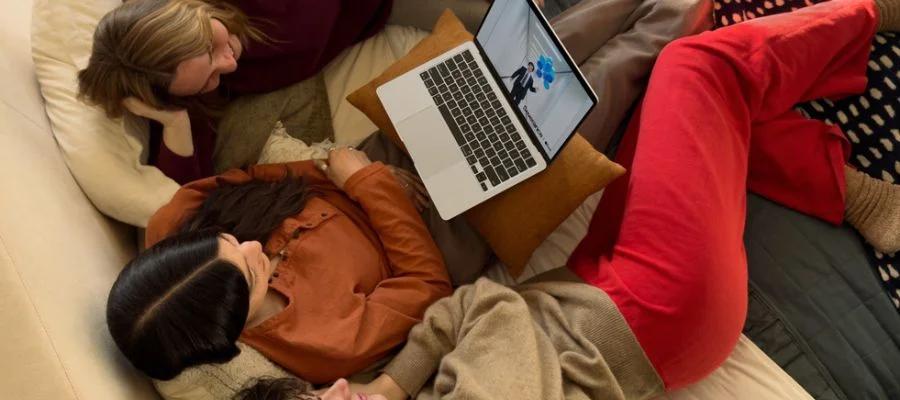 Three young women on a sofa or bed watching a show on the MacBook Air M4