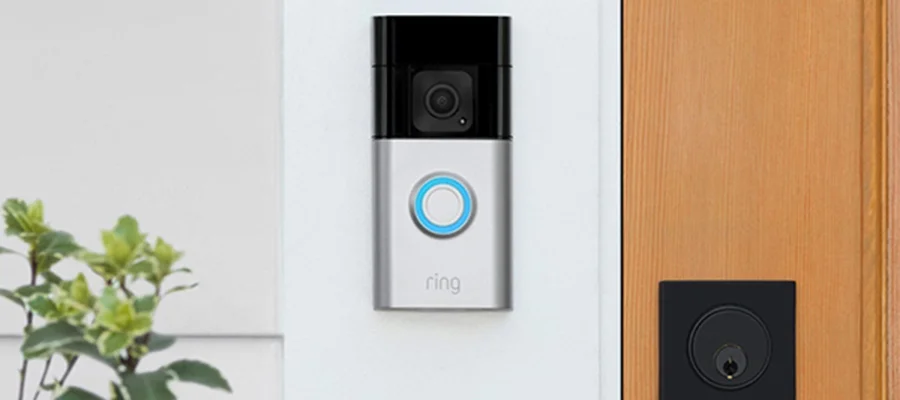 A silver Ring Battery Doorbell Plus mounted outside of a residential home's front door