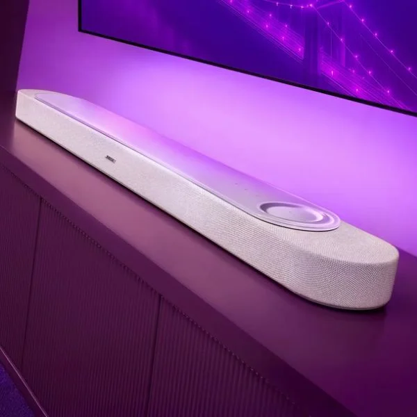 A white Bose Lifestyle Ultra soundbar sits on top of a TV stand under a mounted TV.