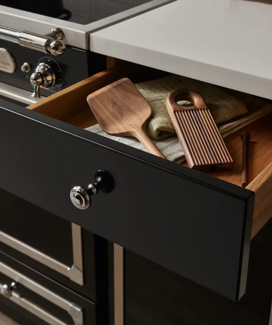 Open drawer on a La Cornue range holding wooden kitchen utensils