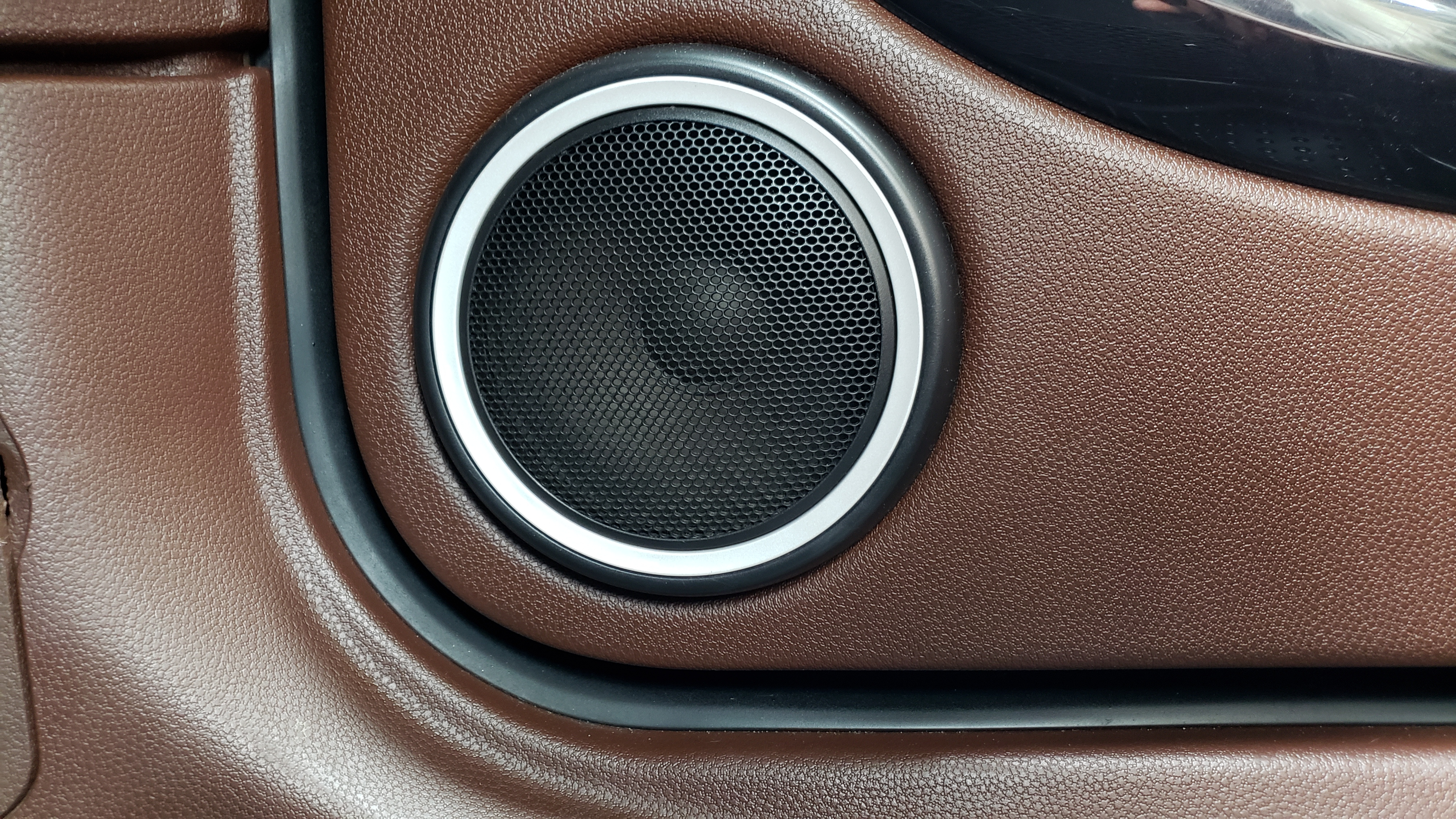 A speaker set into the brown leather of a car's interior