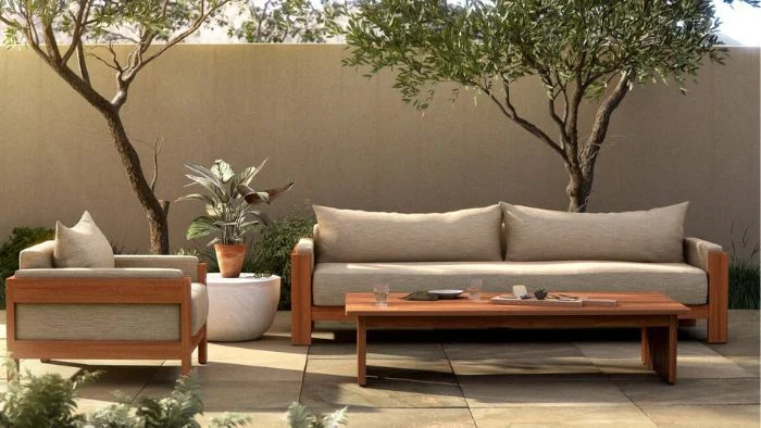 Tan outdoor sofa and arm chair on a patio with trees and shrubbery