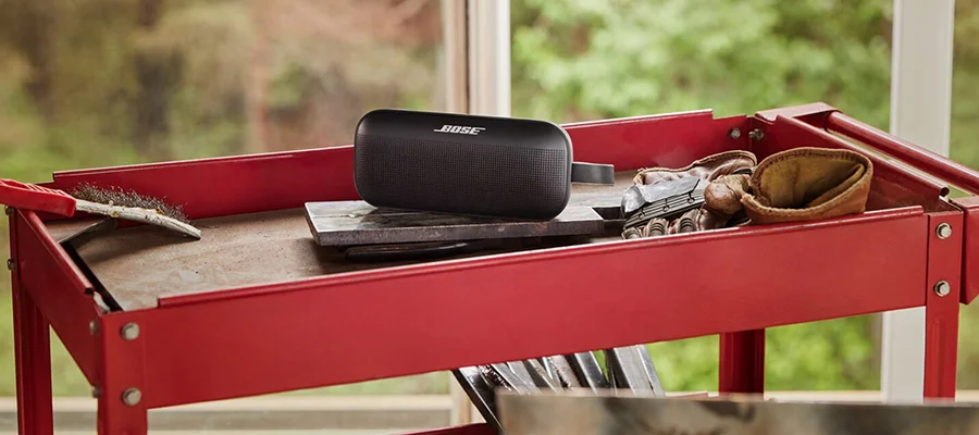 A black Bose Soundlink Flex sitting on a red cart with work supplies