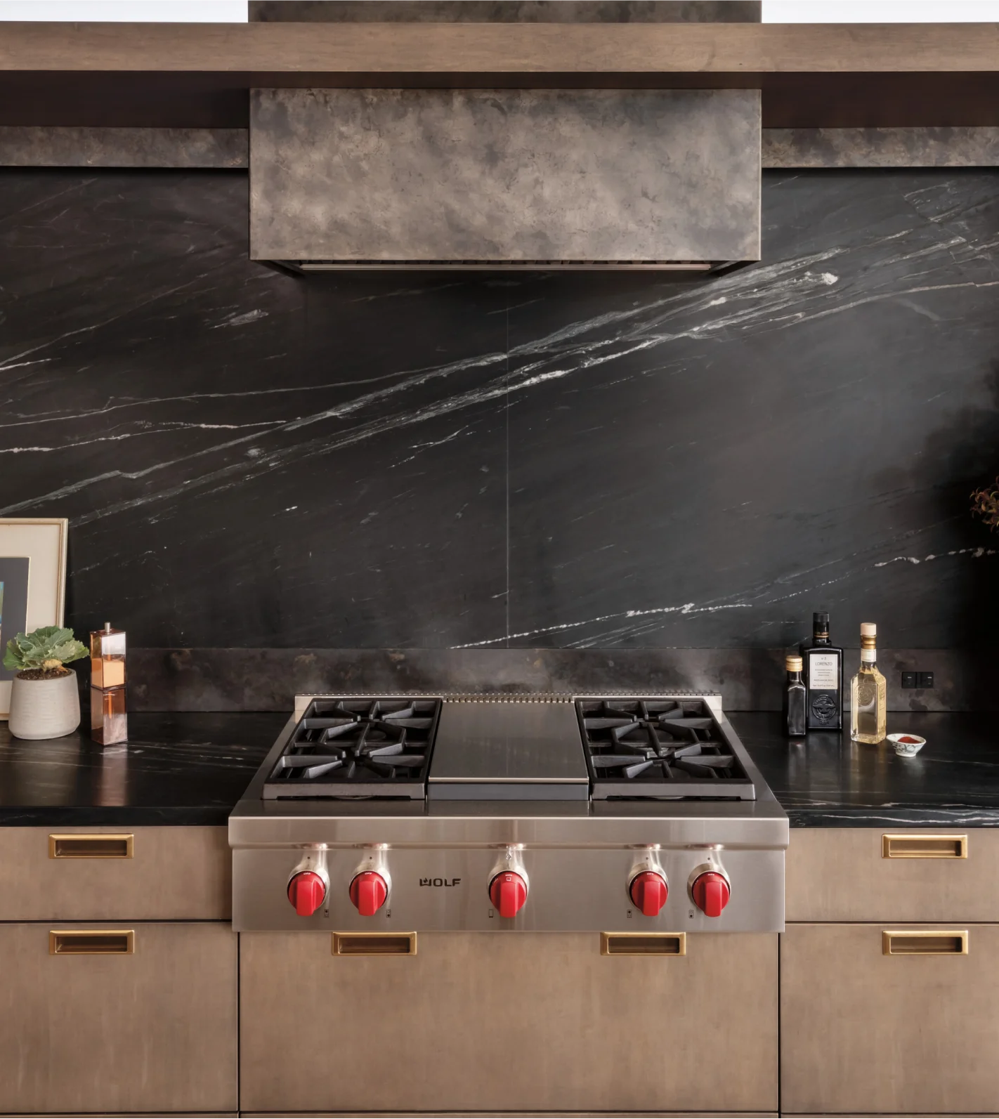 Elegant black and gold kitchen design featuring a built-in Wolf cooktop, combining luxury with culinary efficiency