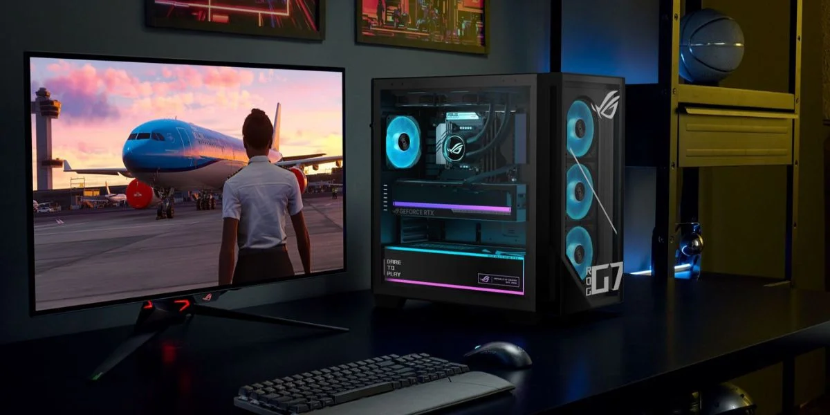 A colorful gaming PC desktop complete with monitor, keyboard and mouse in a bedroom.