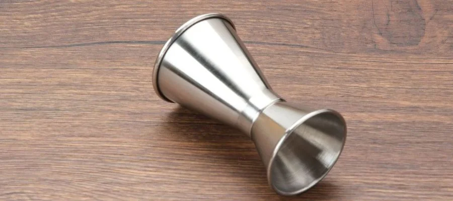Stainless steel jigger laying sideways on wood