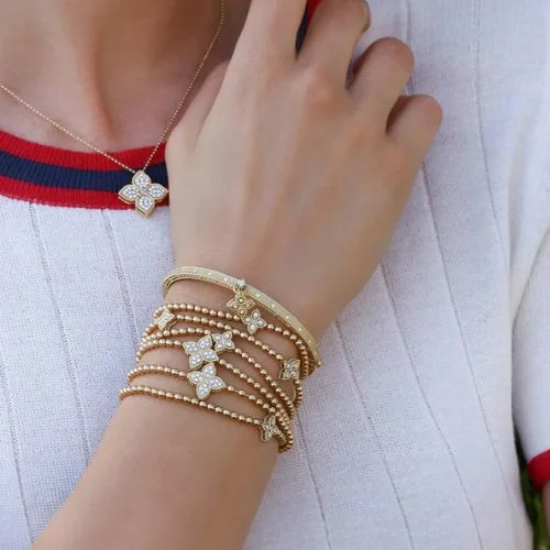 A woman wearing a tan suit with a chain link Roberto Coin necklace stacked with another Roberto Coin Necklace