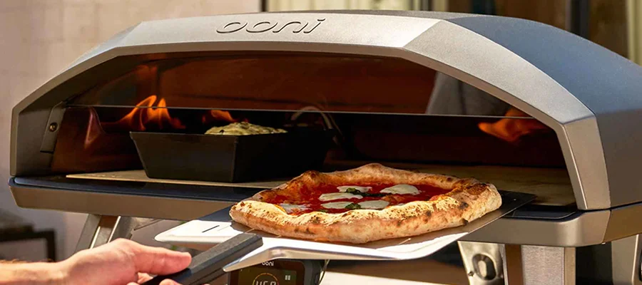 Someone putting a pizza into the Ooni Koda 2 Max using a pizza peel.