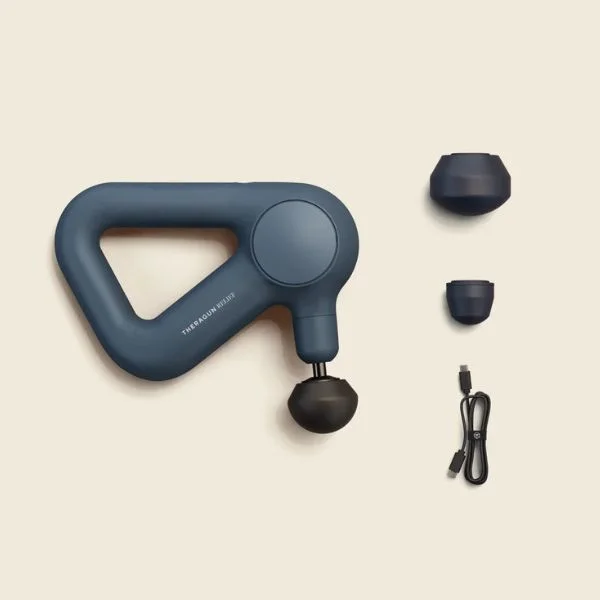 Flat lay of Theragun Relief massage gun and its attachments