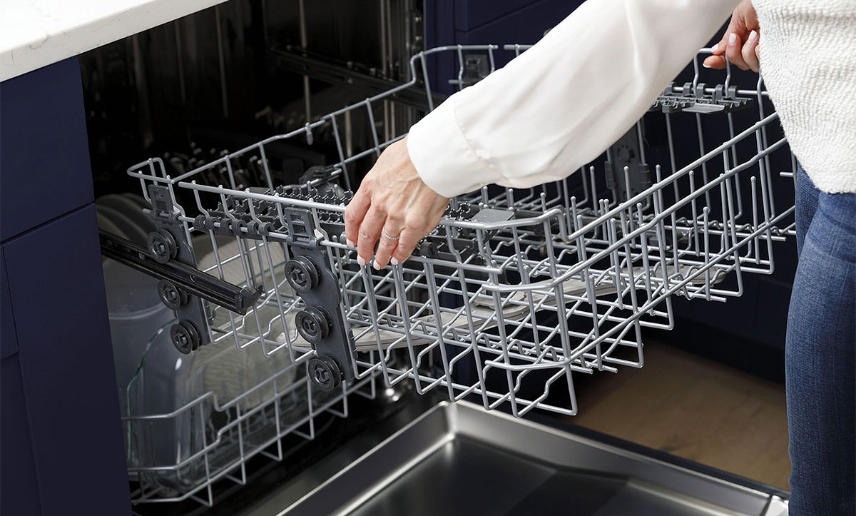 Woman Adjusting Upper Rack on a Stainless Steel GE Dishwasher