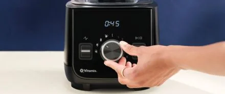 A close-up of the Vitamix Ascent X2 and a person turning the dial