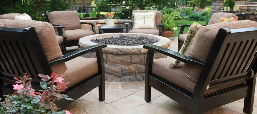 Cushioned outdoor chairs surrounding a fire table outdoors.