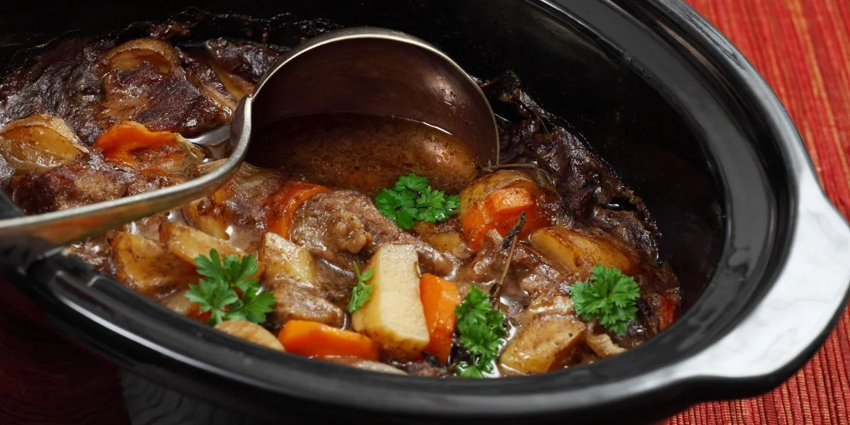 Open slow cooker with veggies simmering inside