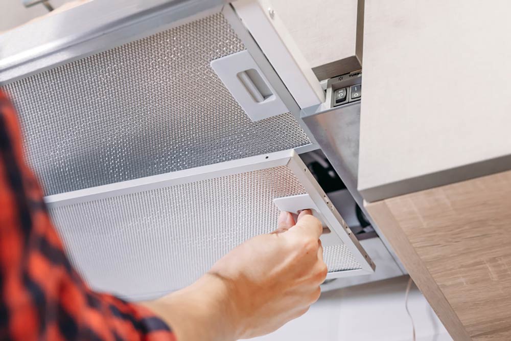 Person checking panels on the range hood