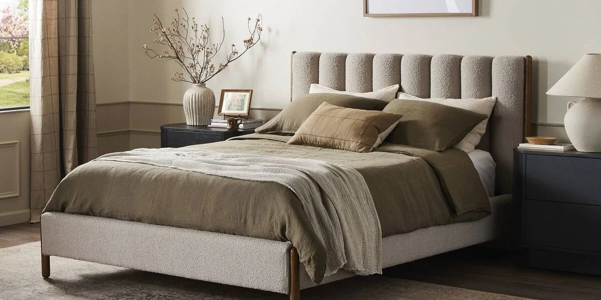 boucle bed frame with boucle headboard made with pillows and blankets in shades of beige and olive green