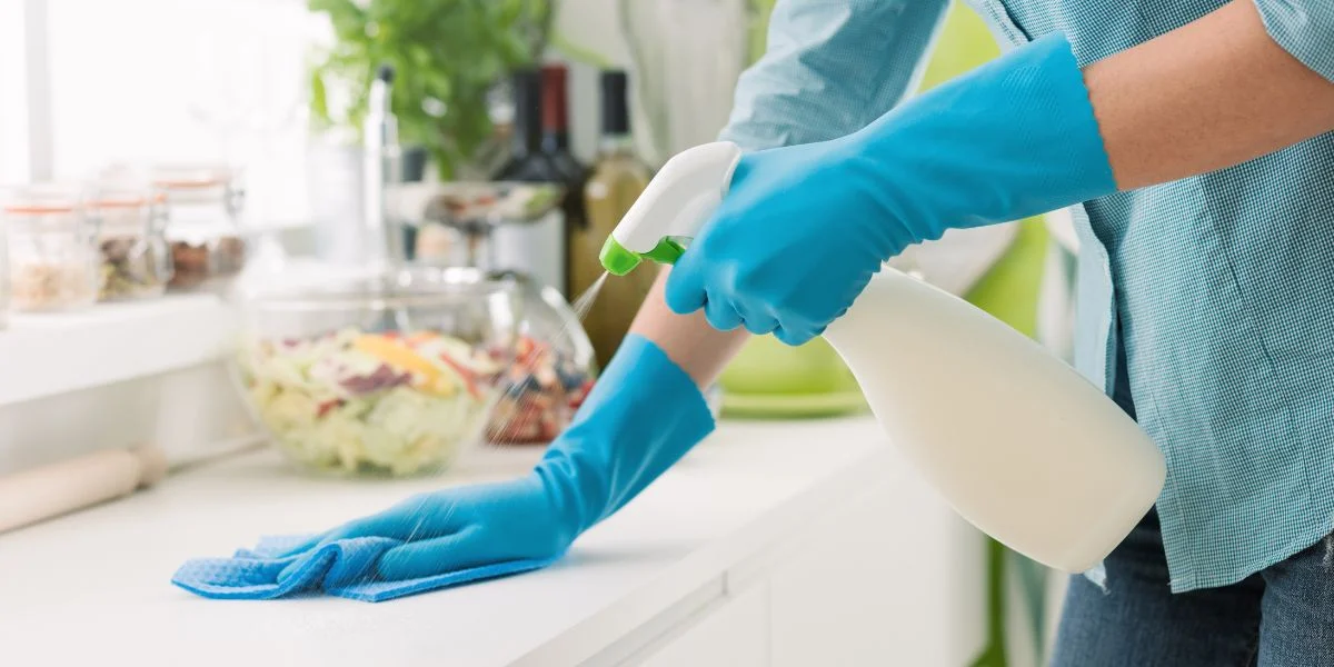 Woman Cleaning Countertops with a spray, sponge and gloves