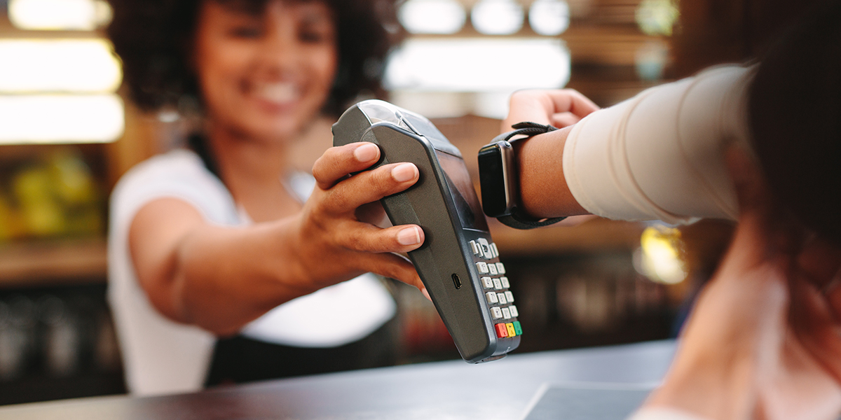A person wearing a smartwatch tapping it against a credit card terminal