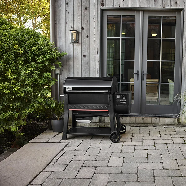 The Weber Searwood 600 XL sitting on a stone patio in front of glass doors