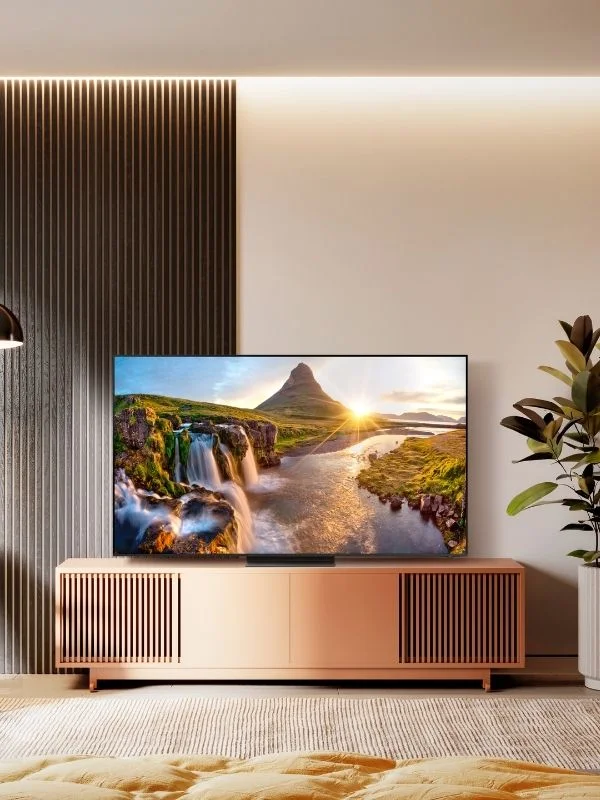 QLED TV with a rainfall and mountscape on the tv that is sitting atop a light brown entertainment center