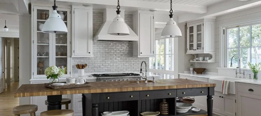 A kitchen designed by Natalie with white cabinets and a large butcher block island in the center.