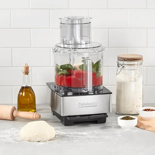The Cuisinart Custom 14 Cup food processor sitting on a countertop next to dough and ingredients while a red mixture sits in the bowl