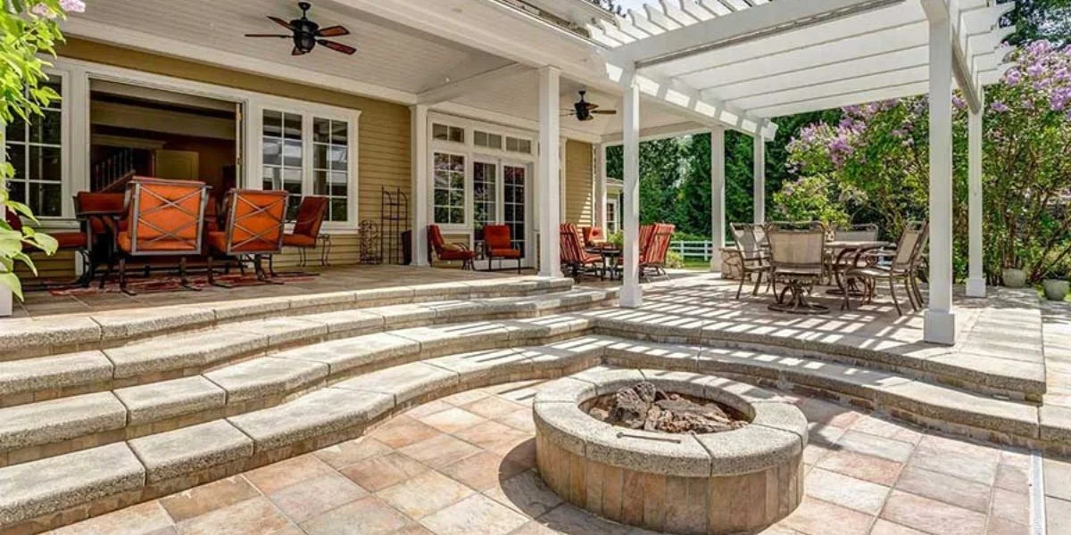 Large patio with three separate tables and chairs and a stone fire pit.