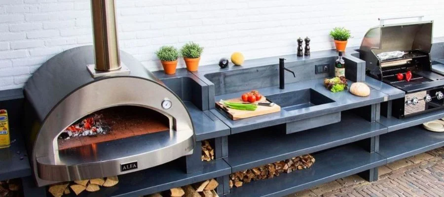 An alfa pizza oven on an outdoor kitchen bar beside a sink and grill.