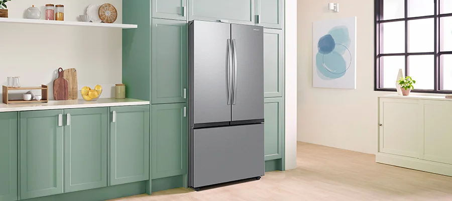 A stainless steel Samsung refrigerator installed in a kitchen with green cabinetry